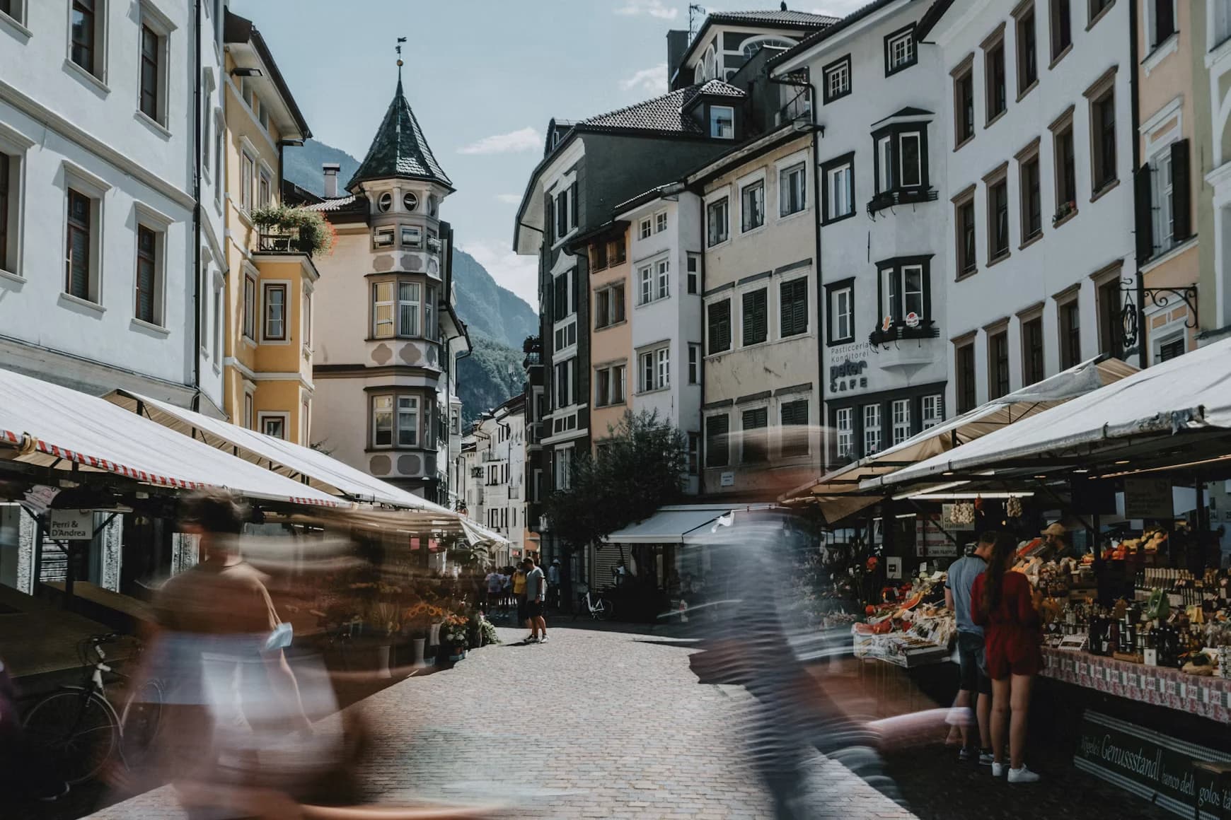 Marktgasse in der Bozener Altstadt, dahinter der Erker eines Bürgerhauses und die Berge