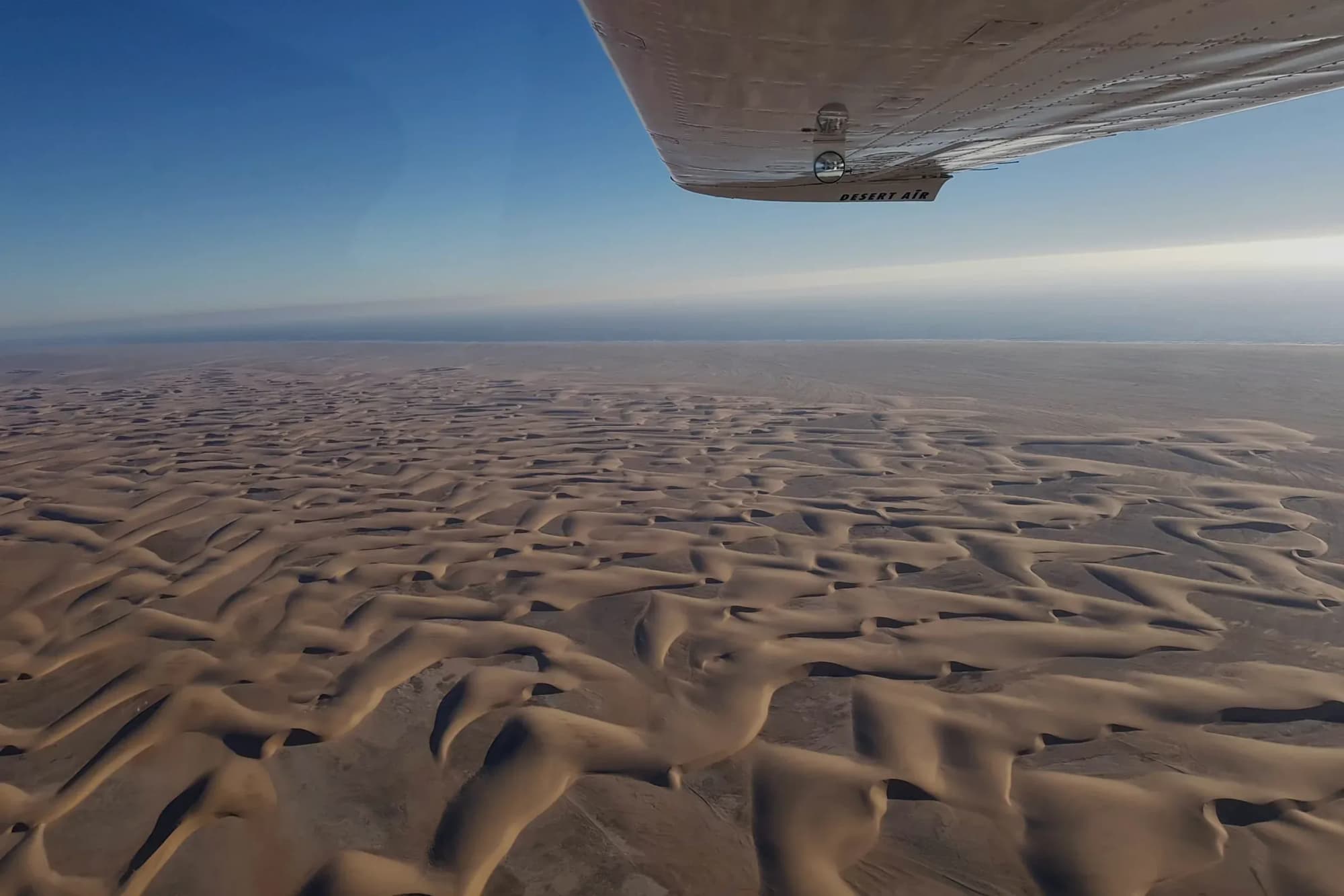 Blick über die Tragfläche der Cessna auf das Dünenmeer der Namib