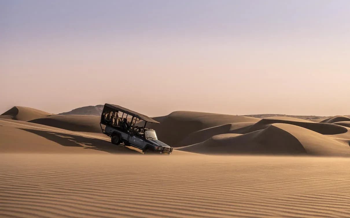Safarifahrzeug auf einer Düne nahe der Serra Cafema Lodge