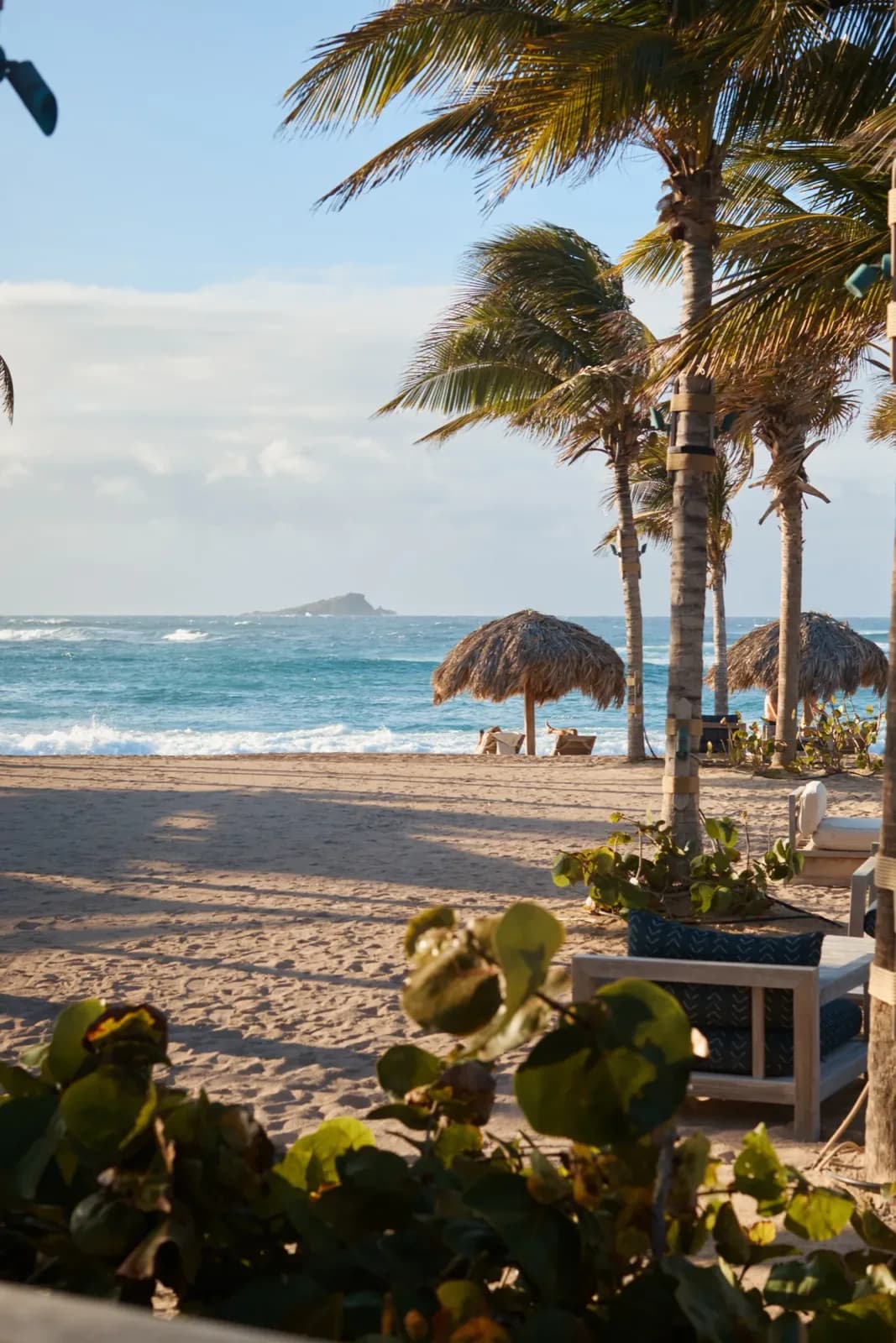 Rosewood Le Guanahani – Strand mit Palmen und Schirmen aus Palmwedeln