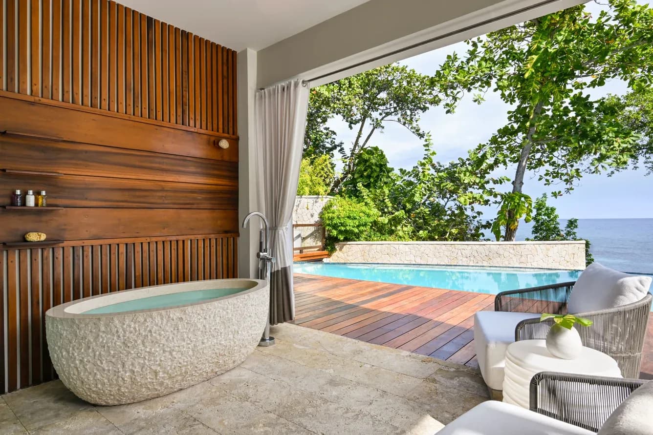 Suite mit freistehender Wanne und Blick zum Pool